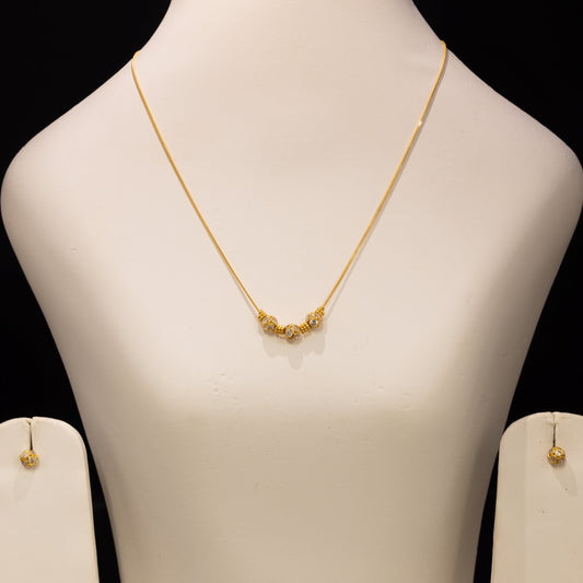 Gold necklace and matching stud earrings displayed on a white jewelry bust against a black background.
