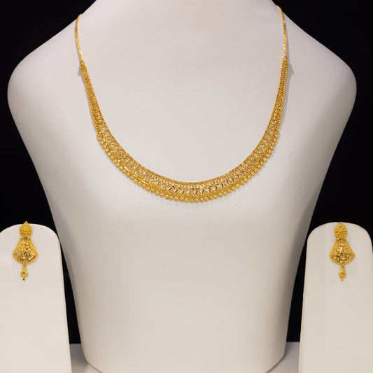 Gold necklace and matching earrings displayed on a white jewelry bust against a black background.