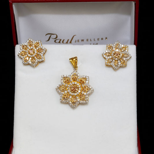 Gold floral earrings in a Paul Jewellers box on a black background