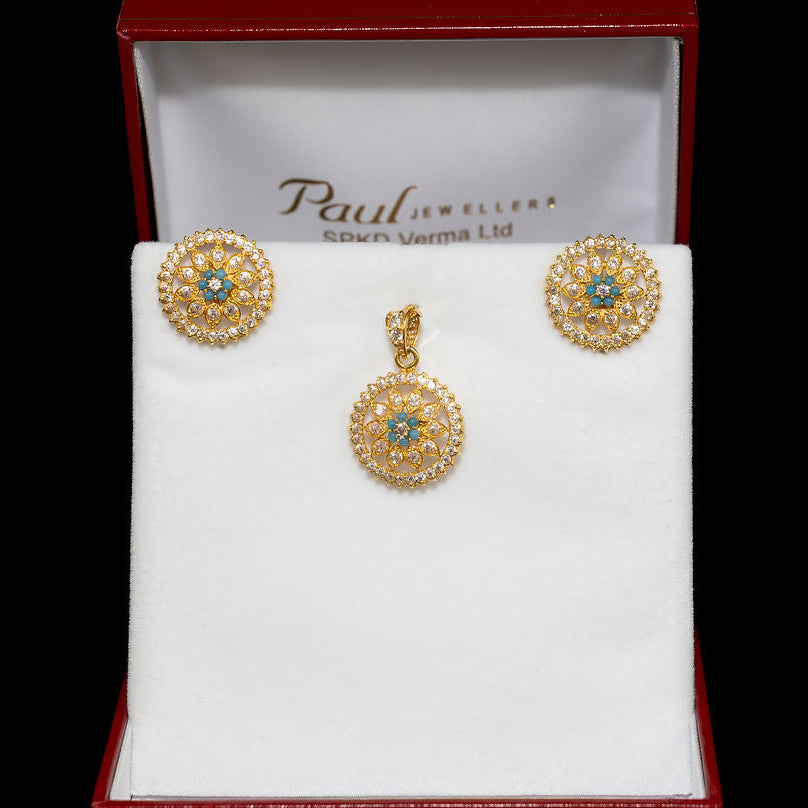 Gold earrings with gemstones in a Paul's Jewellers box on a black background