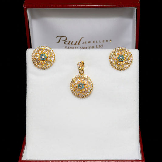Gold earrings with gemstones in a Paul's Jewellers box on a black background