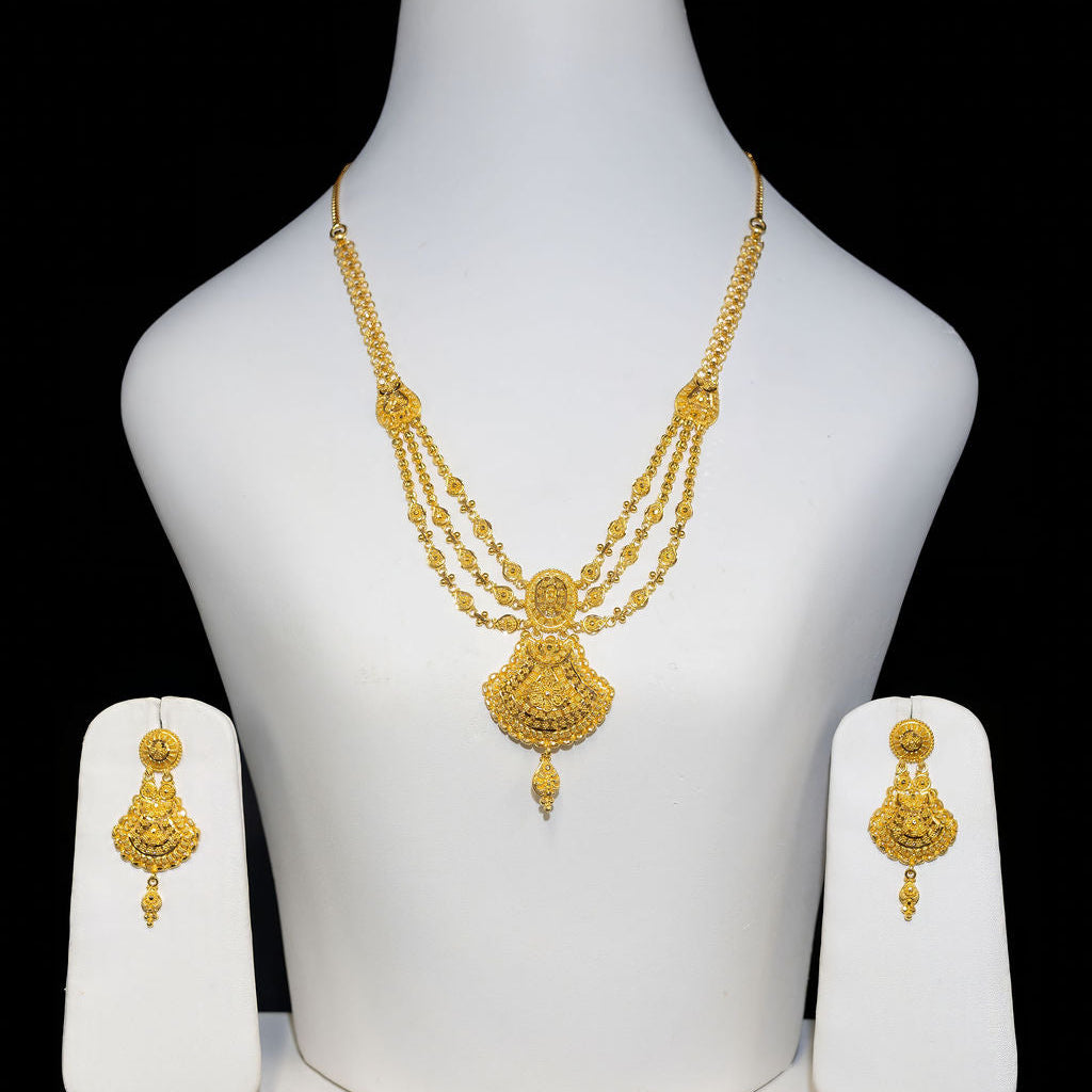Gold necklace and earrings set on a white mannequin bust against a black background