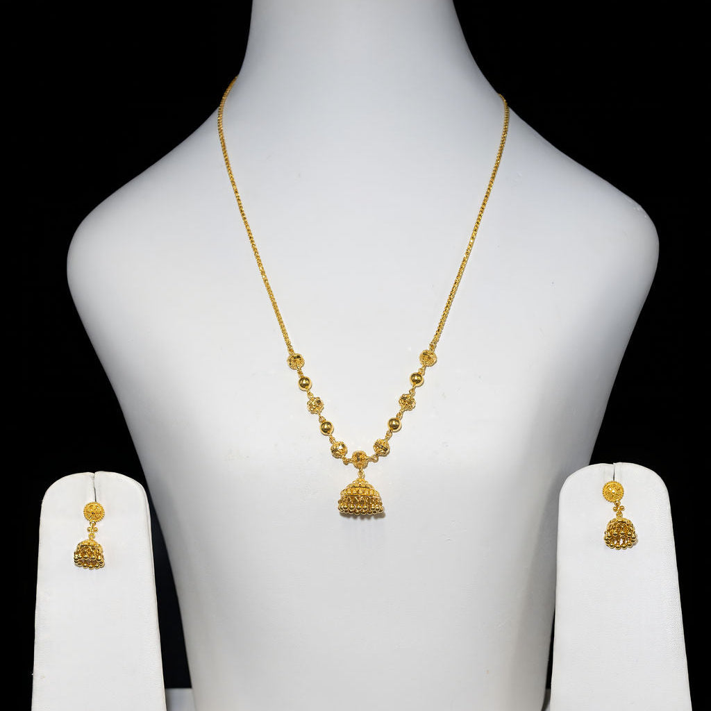 Gold necklace and earrings set on a white mannequin bust with a black background