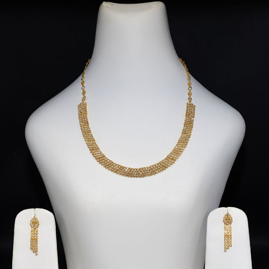 Gold necklace and earrings set on a mannequin bust against a black background