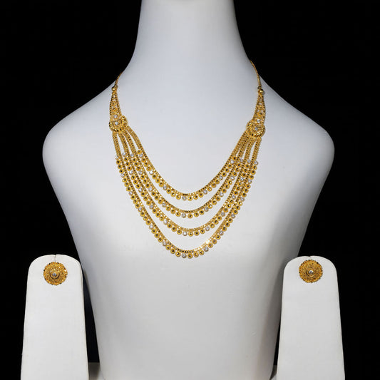 Gold necklace and earrings on a white mannequin bust against a black background